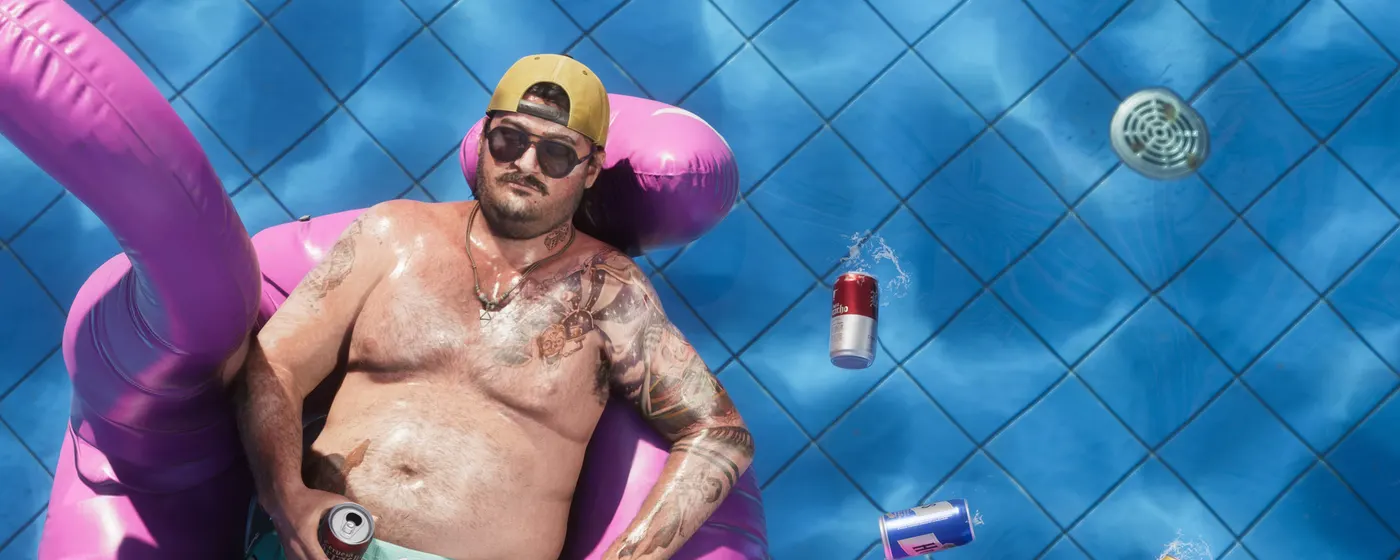 A tattooed man floating on a pink inflatable in a swimming pool in Grand Theft Auto VI